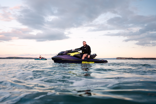 Rider aboard a Sea-Doo RXT on calm Auckland water at dusk