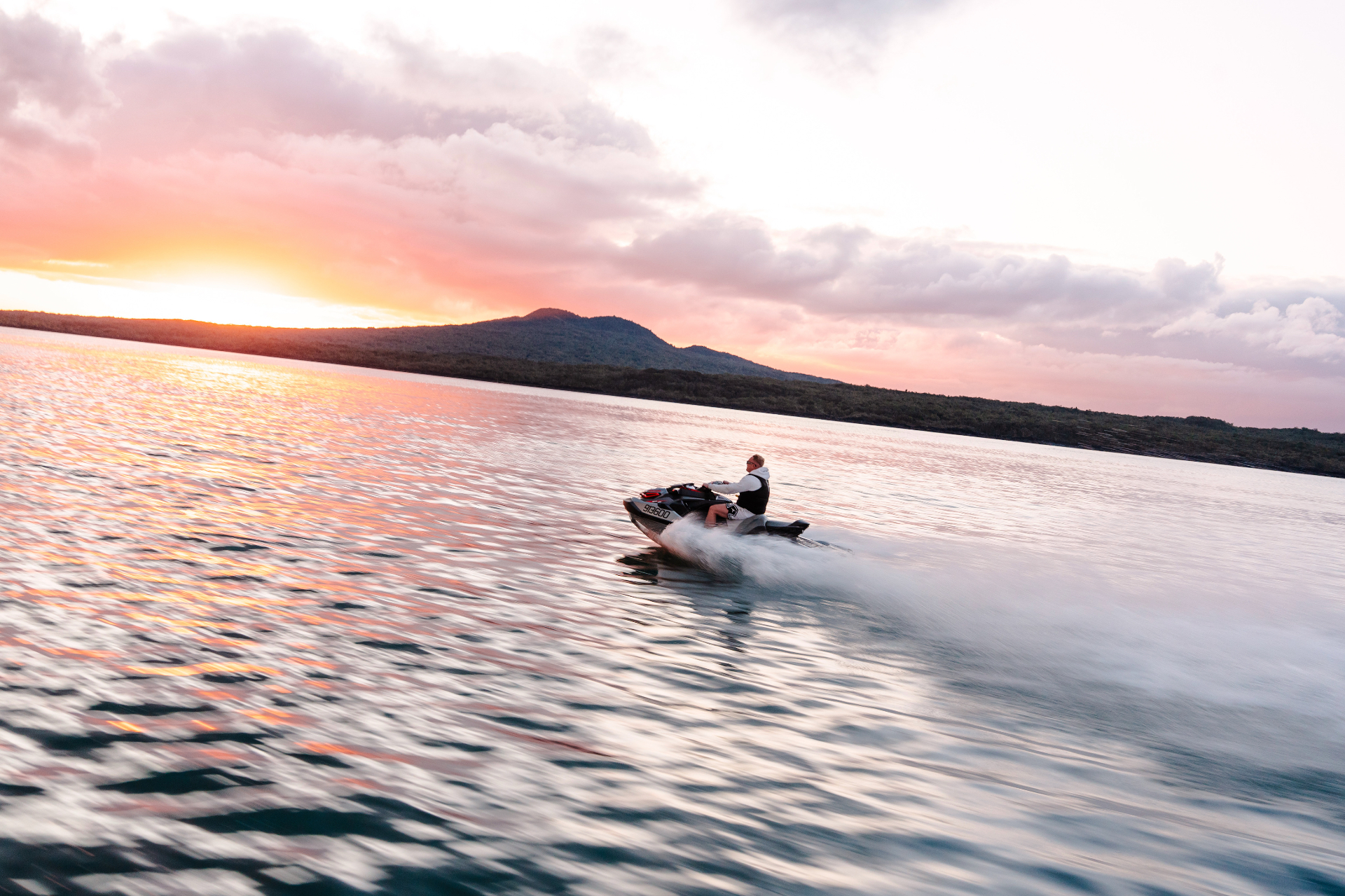 Jetski cruising past Rangitoto at sunset on the Hauraki Gulf